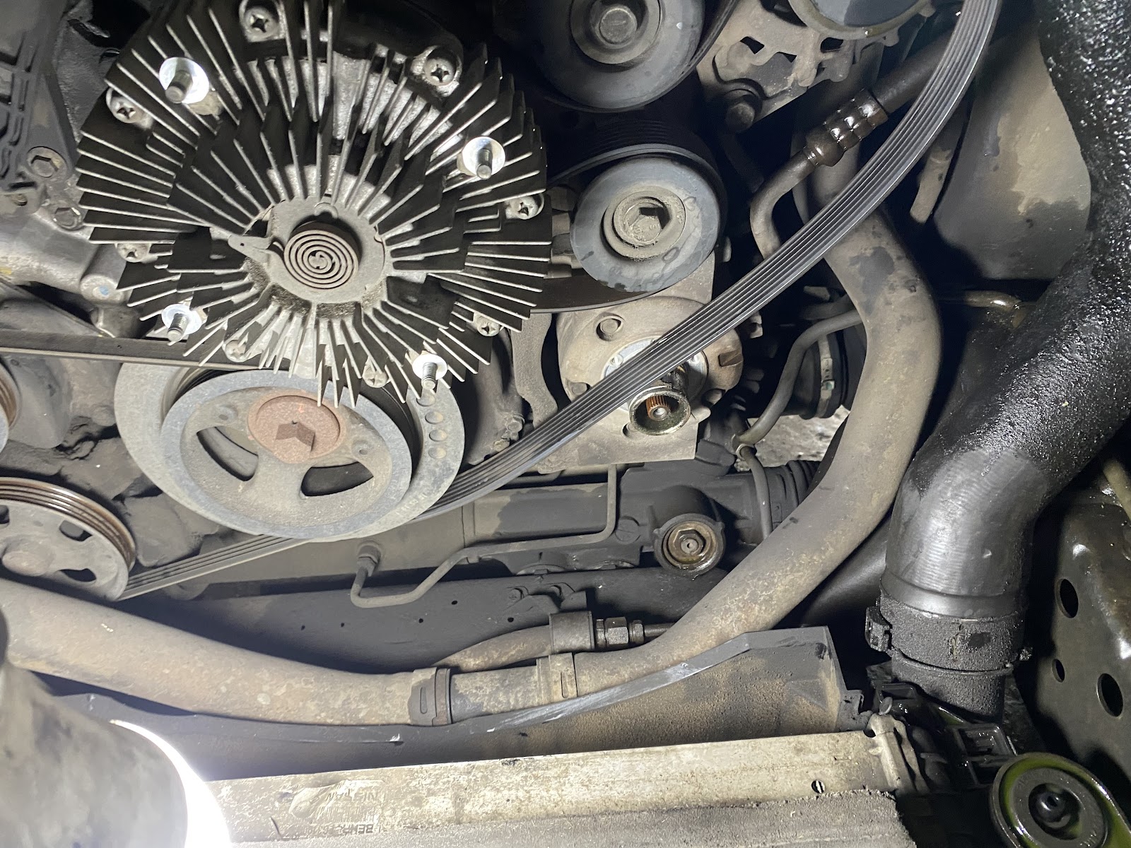 Detalle de las correas, poleas y compresor del sistema de aire de un motor