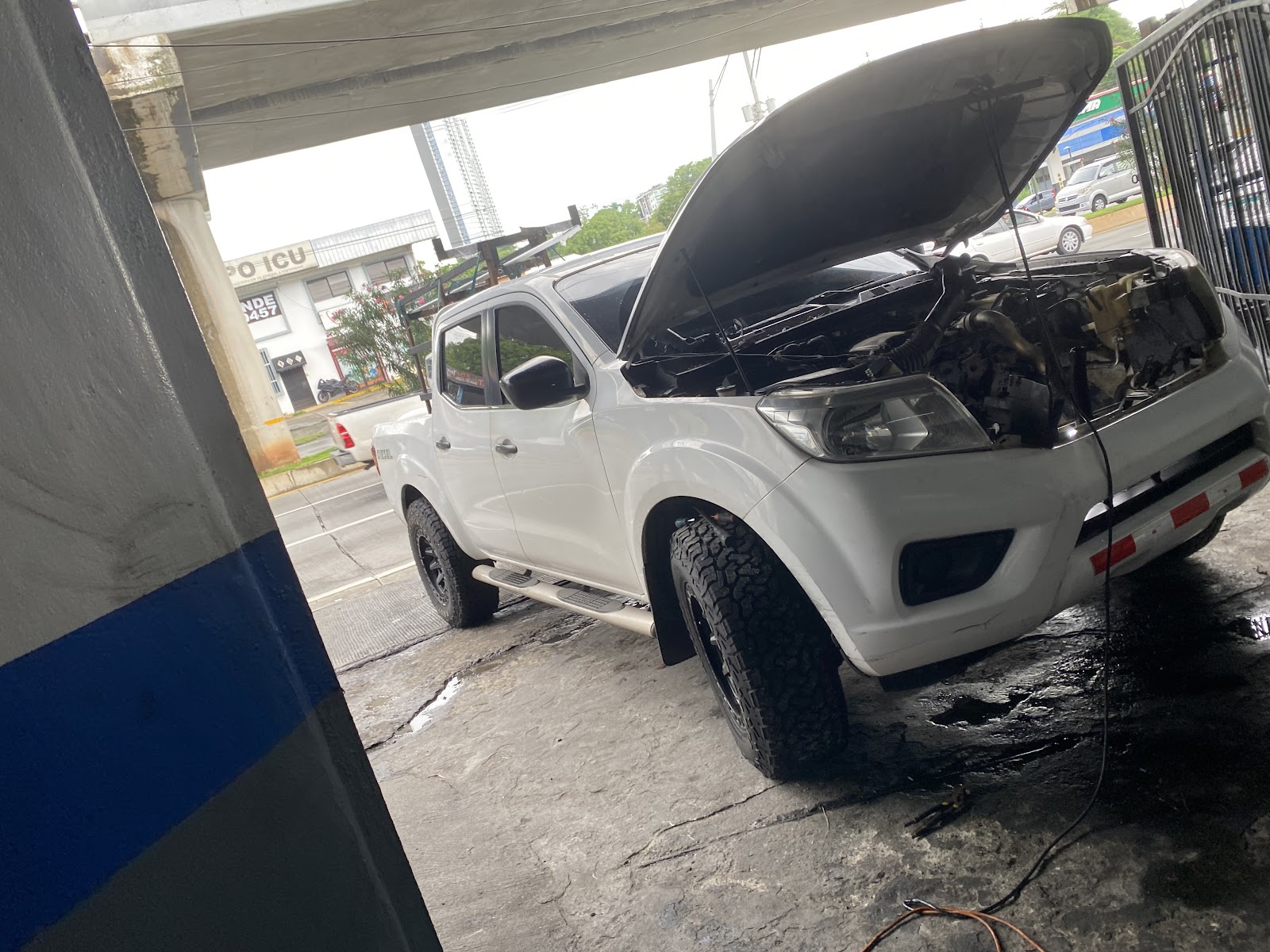 Pickup blanca con el capó abierto durante la reparación del aire acondicionado